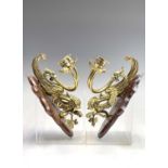 A pair of Victorian brass dragon candle sconces, the twin nozzles issuing from the beasts mouth,
