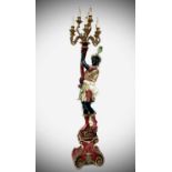 A carved, painted and gilt floor standing figural candelabra, 20th century, in the form of a