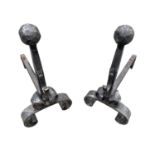 A pair of wrought iron fire dogs, mid 20th century, in the Arts and Crafts style, height 53cm.