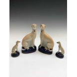 A pair of Staffordshire seated figures of greyhounds, 19th century, on blue bases, together with a