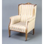 An Edwardian inlaid mahogany winged armchair upholstered in Regency stripe material The frame is