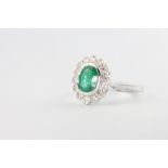 An 18ct white gold oval emerald and diamond cluster ring, the centre stone approx. 1.25ct, the 14