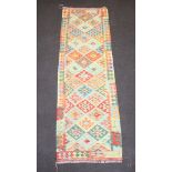 A tan, yellow and green ground Chobi Kilim runner with all over geometric design 248cm x 77cm