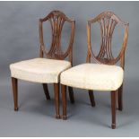 A pair of 19th Century Hepplewhite style shield back dining chairs with over stuffed seats, raised