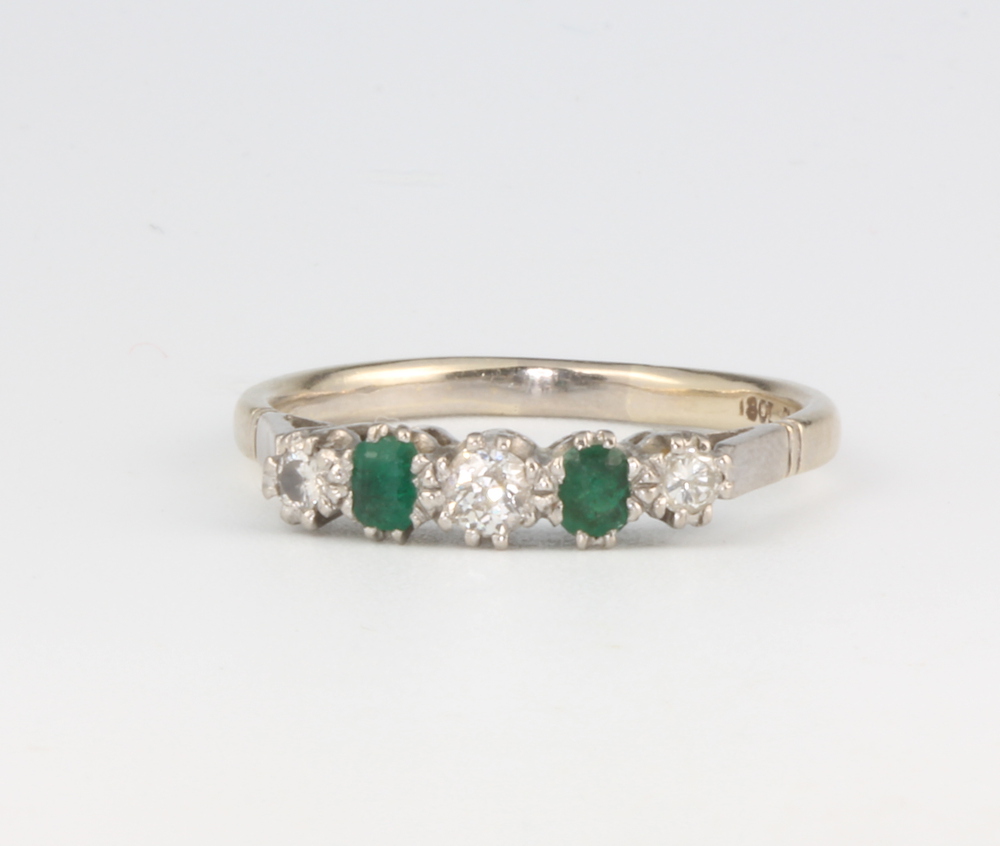 An 18ct white gold emerald and diamond ring, the 3 brilliant cut diamonds approx. 0.17ct, the 2 oval