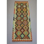 A tan, yellow, black and green ground Chobi Kilim runner with all-over diamond design 196cm x 63cm