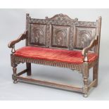 A Victorian carved oak settle with raised panel back, on turned and block supports with box frame