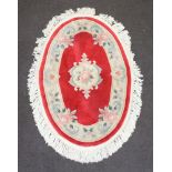An oval red and white floral patterned Indian rug 131cm x 323cm Some staining and pulling