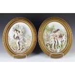 A pair of late 19th Century German porcelain oval plaques depicting figures in garden landscapes,