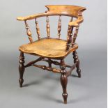 A 19th Century elm smokers bow chair with spindle decoration and solid seat, raised on turned