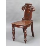 A Victorian carved oak hall chair with shield shaped back and solid seat, raised on turned and