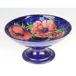 A Walter Moorcroft blue ground pedestal bowl decorated with anemones 19cm