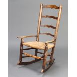An 18th Century elm ladder back rocking armchair with woven rush seat