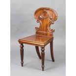 A Georgian mahogany hall chair with shaped back and solid seat raised on turned and reeded supports