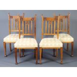 A set of 4 Art Nouveau Liberty style carved oak stick and rail back dining chairs with over
