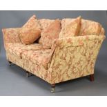 A Victorian style 2 seat sofa upholstered in floral patterned material raised on turned feet,