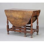 An 18th Century oak oval drop flap gateleg dining table fitted a frieze drawer raised on turned