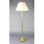 An Art Nouveau brass adjustable standard lamp raised on a circular base with panel feet