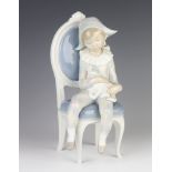 A Lladro figure of a seated Pierrot child holding a cat 25cm