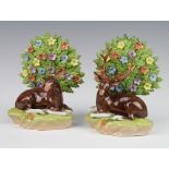 A pair of modern Dresden porcelain figures of seated deer before floral encrusted trees, raised on