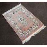 A peach ground and floral patterned Chinese rug with central medallion 189cm x 126cm Some staining