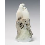 A Royal Copenhagen group of 2 budgerigars sitting on a trunk 649 18cm