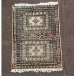 A white and black ground Bokhara rug, 2 panels to the centre within a multirow border 88cm x 62cm