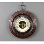 An Edwardian aneroid barometer, the 9cm circular, enamelled dial contained in a carved circular