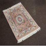 A peach ground and floral patterned Chinese rug 163cm x 92cm Some staining in places