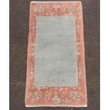 A turquoise and peach ground Chinese rug with signature to base 138cm x 69cmThe fringe has been