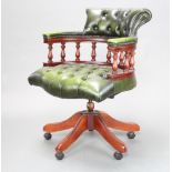 A mahogany revolving captain's/office chair upholstered in green buttoned leather with spindle