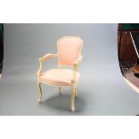 A limed oak Empire style open armchair upholstered in pink and white material, raised on cabriole