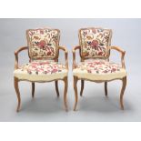 A pair of French style beech open arm chairs, the seats and backs upholstered in floral Berlin