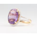 An oval amethyst and diamond cluster ring, the centre stone approx. 6.92ct surrounded by brilliant