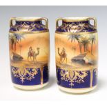 A pair of Art Deco Noritake 2 handled cylindrical vases decorated with Egyptian scenes, figures