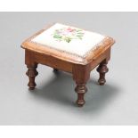 A Victorian rectangular mahogany footstool with floral Berlin wool work seat, raised on turned