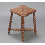 A Victorian shaped and carved oak stool raised on spiral turned supports with H framed stretcher