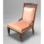 A Victorian carved walnut nursing chair upholstered in pink dralon with bobbin decoration raised