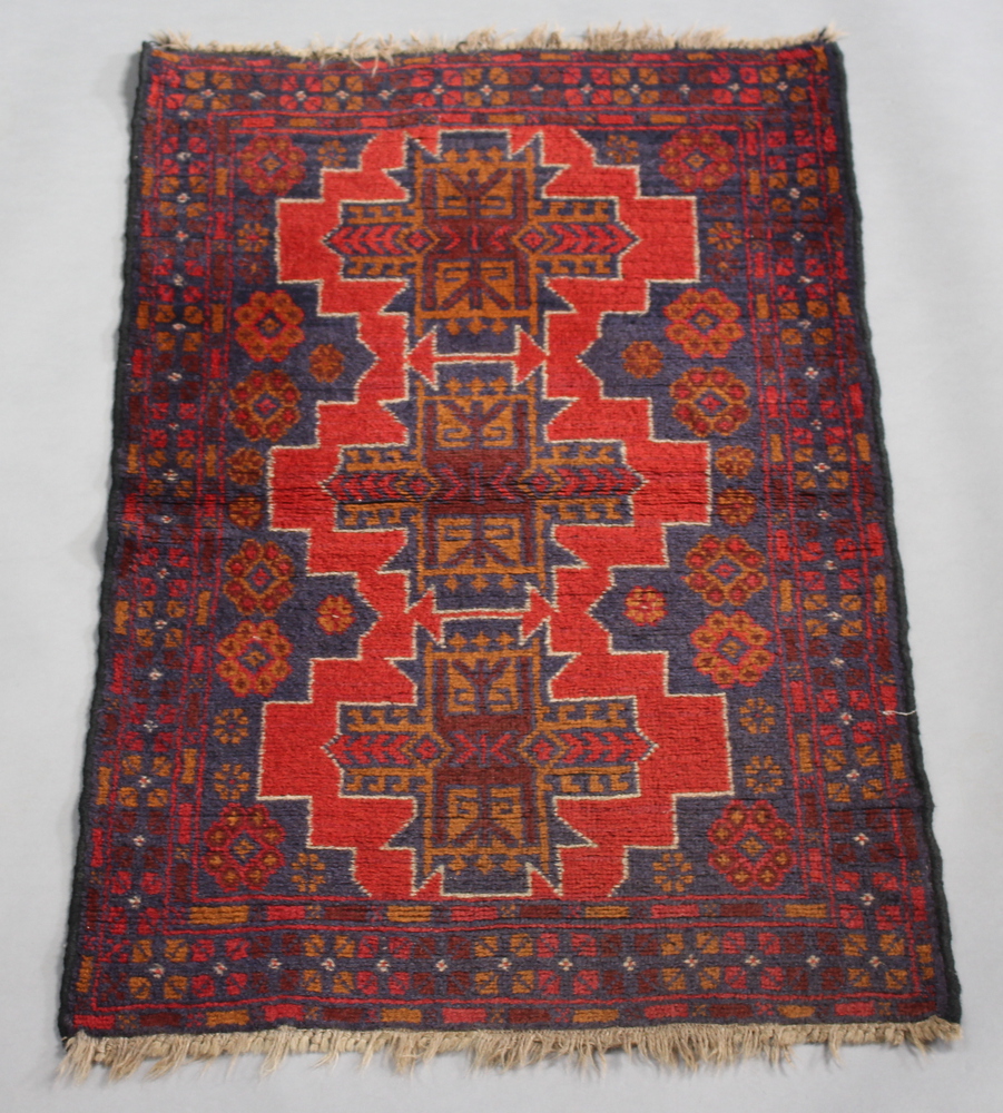 A red and blue ground Belouche rug with 3 stylised diamonds to the centre 136cm x 85cm