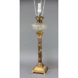A cut glass oil lamp reservoir raised on a gilt metal ivy clad column with Corinthian capital and