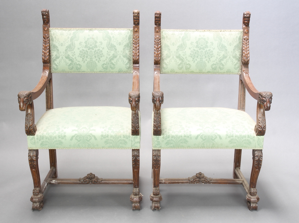 A pair of Italian style carved walnut open arm chairs with mask and rams head decoration, the