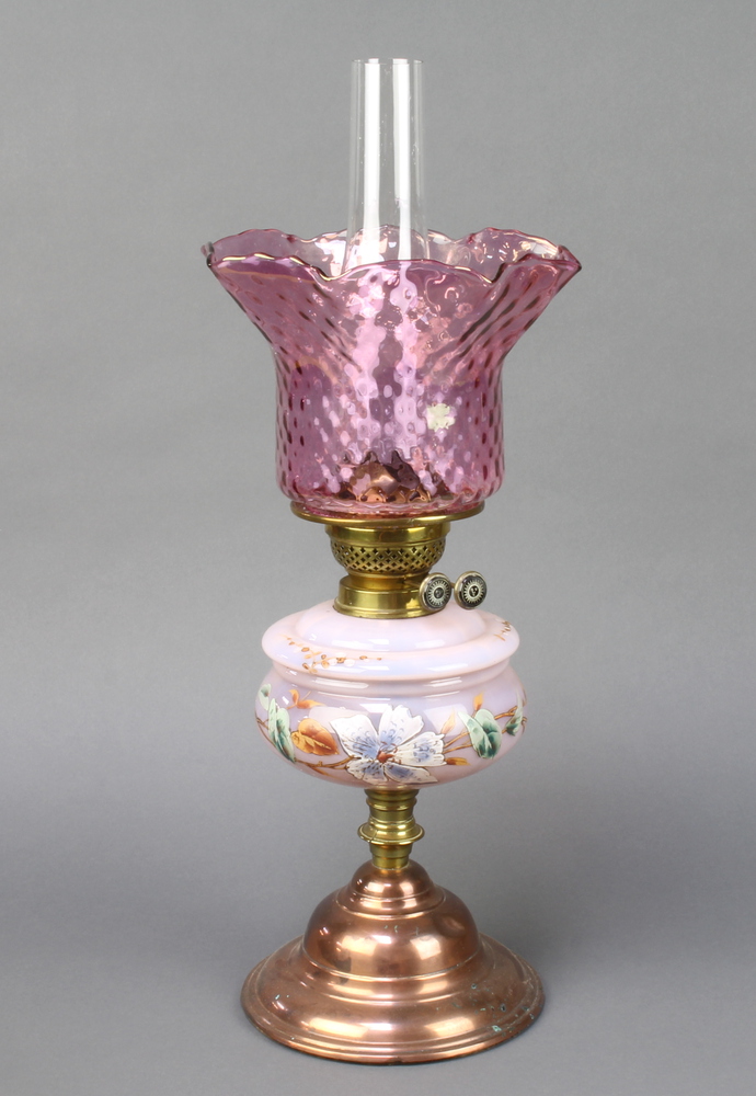 A Victorian opaque pink and floral painted oil lamp reservoir with shade and chimney, raised on a