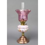 A Victorian opaque pink and floral painted oil lamp reservoir with shade and chimney, raised on a
