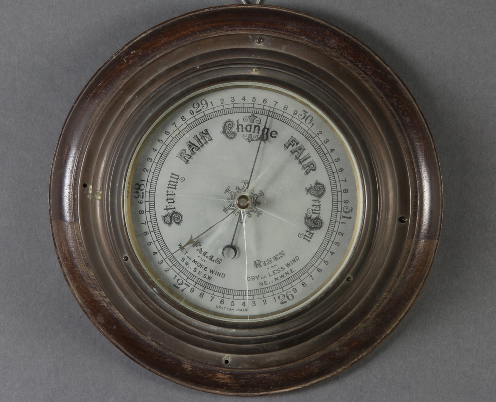 An aneroid barometer with silvered dial, contained in a gilt metal case 4cm x 27cm diam. The glass