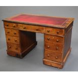 A Victorian oak kneehole pedestal desk with inset leather writing surface above 1 long and 8 short