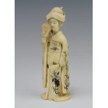 A Japanese carved ivory Meiji Okimono of a standing lady holding a fan and a flower with shibayama