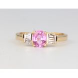 An 18ct yellow gold pink sapphire and baguette diamond ring, the centre stone approx. 0.89ct, the