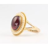 A 9ct yellow gold cabochon cut oval garnet and enamel ring, size S, 7 grams