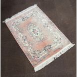 A peach ground and floral patterned Chinese rug with central medallion 192cm x 122cm Some slight