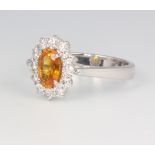 An 18ct white gold orange sapphire cluster ring, the centre stone approx, 1.21ct surrounded by